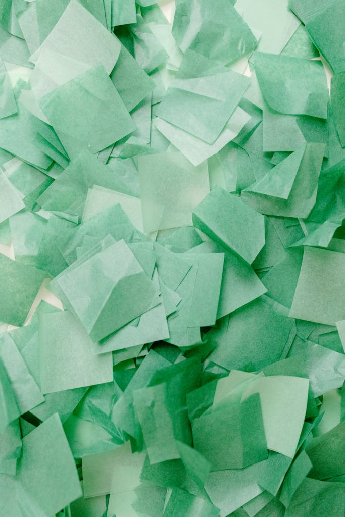 A textured abstract background with overlapping green paper squares, perfect for creative designs.